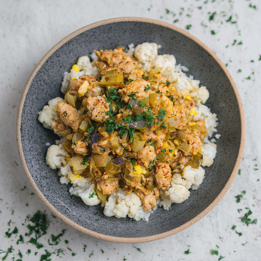 Dish of cauliflower rice with a meat and vegetable mixture on a speckled plate.